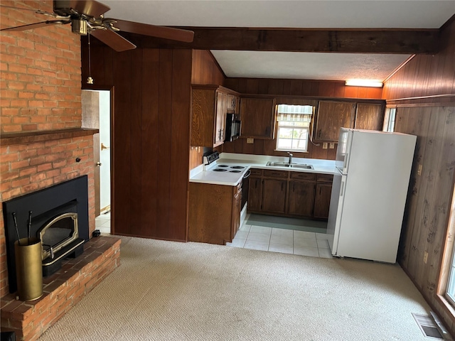 kitchen with light tile patterned floors, white appliances, wooden walls, and beam ceiling