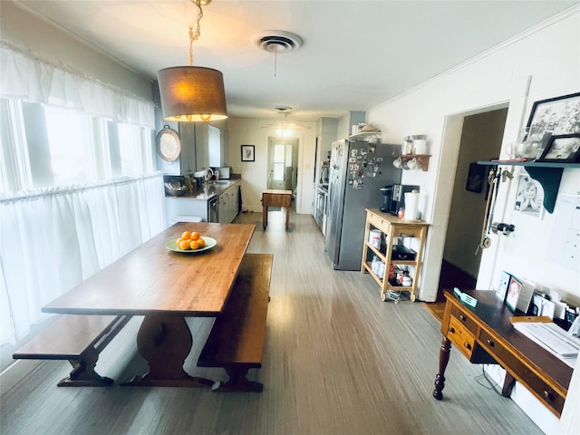 dining room featuring crown molding, light hardwood / wood-style flooring, and sink