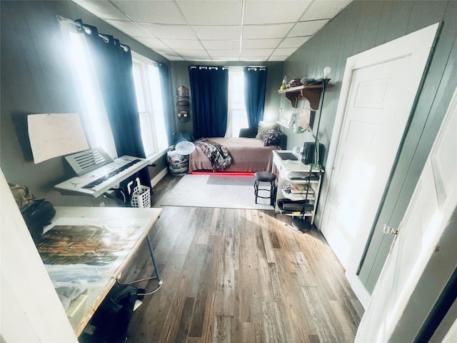 bedroom with a paneled ceiling and wood-type flooring