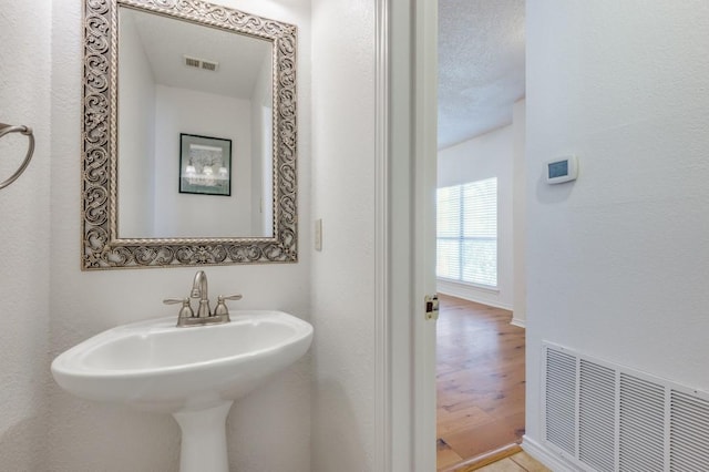 bathroom featuring sink, wood-type flooring, and a textured ceiling