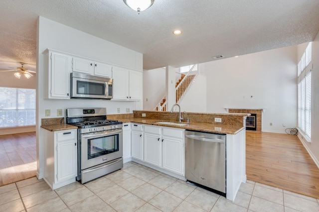 kitchen with kitchen peninsula, stainless steel appliances, white cabinetry, and sink