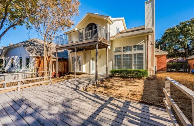 rear view of house featuring a wooden deck and a balcony