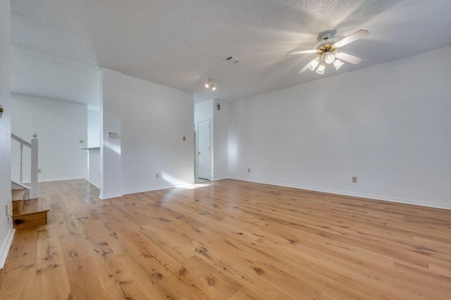 empty room with a textured ceiling, light hardwood / wood-style floors, and ceiling fan