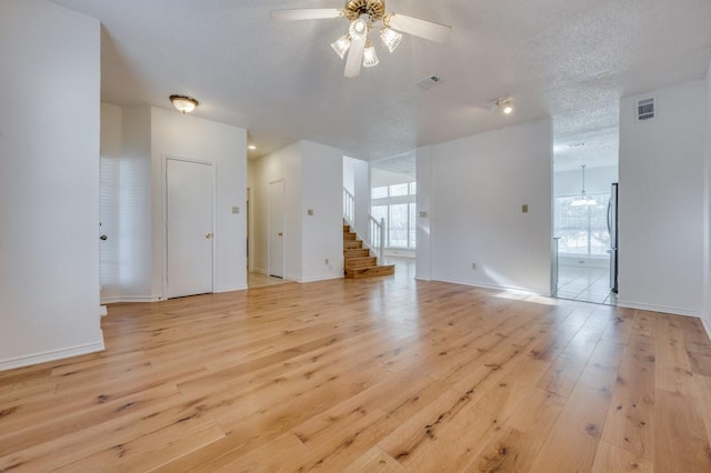 unfurnished living room with a textured ceiling, light hardwood / wood-style floors, ceiling fan, and a healthy amount of sunlight