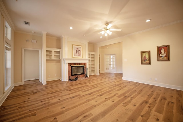 unfurnished living room featuring a brick fireplace, crown molding, ceiling fan, and light wood-type flooring