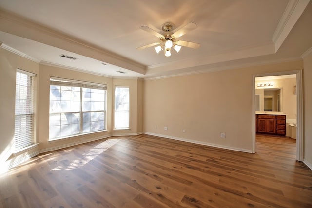 spare room featuring a raised ceiling, ceiling fan, wood-type flooring, and ornamental molding