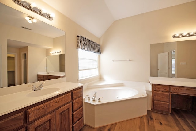 bathroom with a washtub, vanity, wood-type flooring, and vaulted ceiling