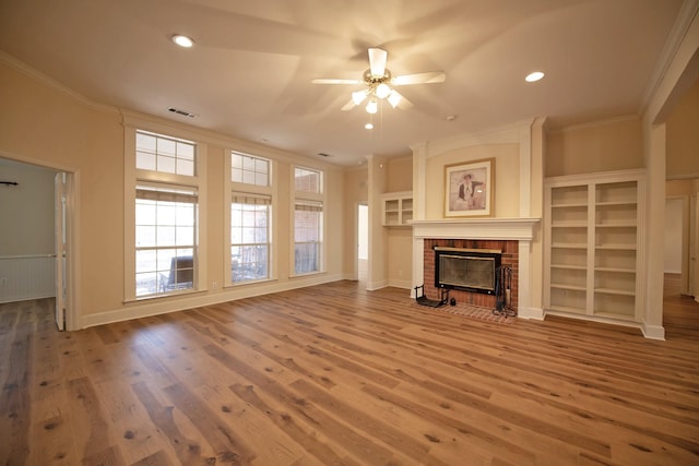 unfurnished living room featuring hardwood / wood-style flooring, ceiling fan, ornamental molding, and a fireplace