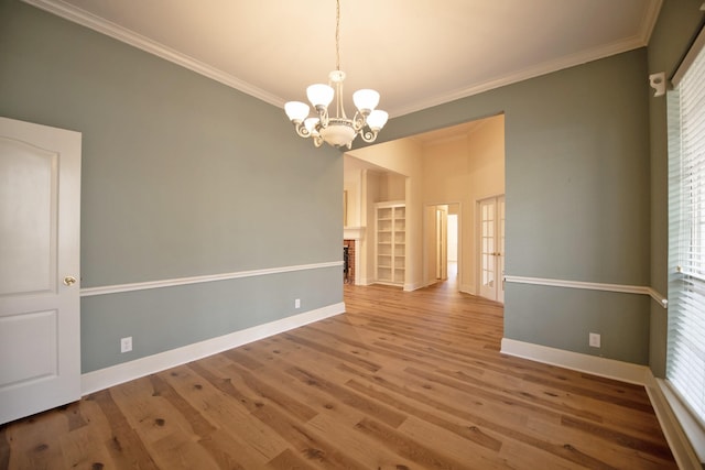 unfurnished room featuring ornamental molding, hardwood / wood-style floors, a brick fireplace, and a notable chandelier