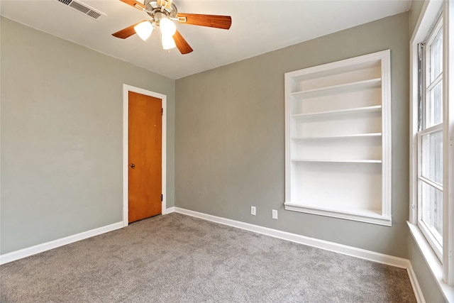 spare room with ceiling fan, light carpet, and built in shelves