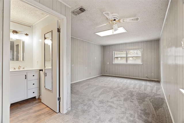 unfurnished room with carpet, a textured ceiling, ceiling fan, and wood walls