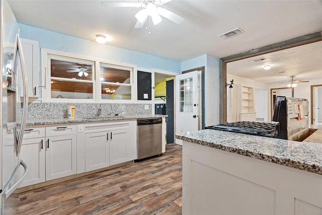 kitchen with light stone countertops, appliances with stainless steel finishes, light wood-type flooring, sink, and white cabinets