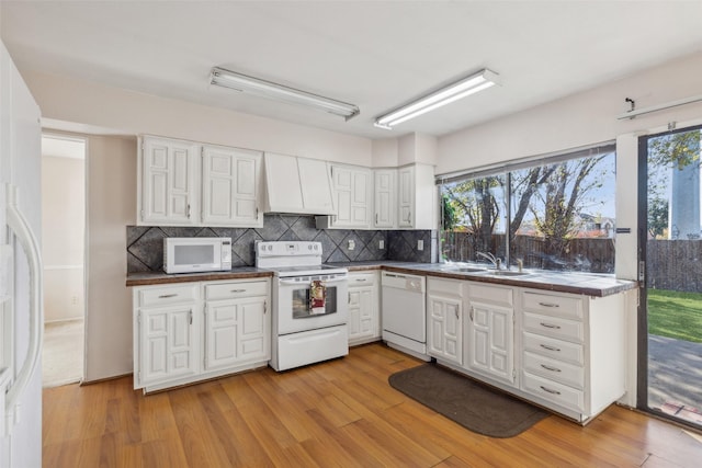 kitchen with custom range hood, white appliances, light hardwood / wood-style flooring, and plenty of natural light