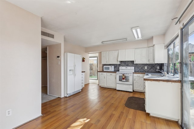 kitchen with white cabinets, plenty of natural light, light wood-type flooring, and white appliances