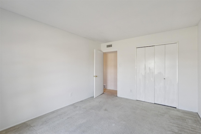 unfurnished bedroom featuring light carpet and a closet