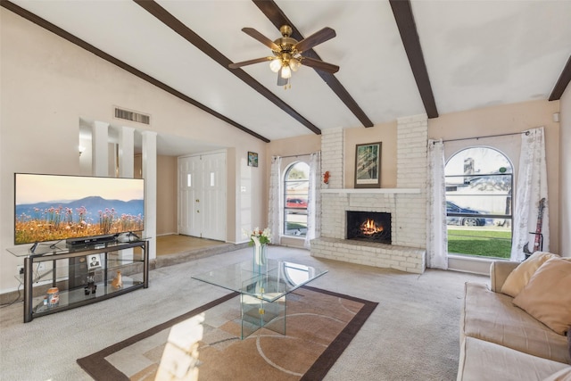 carpeted living room featuring lofted ceiling with beams, a brick fireplace, and ceiling fan