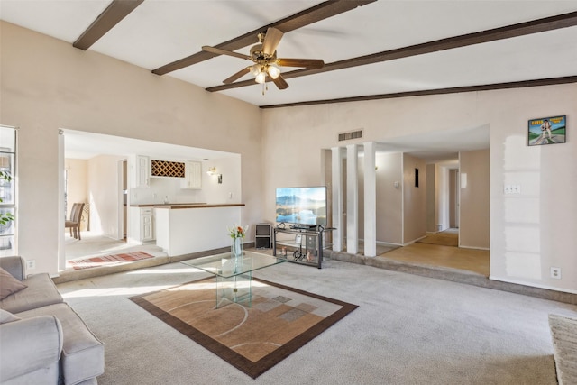 living room with beam ceiling, bar area, light colored carpet, and a high ceiling