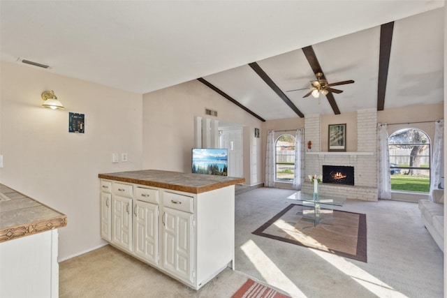 kitchen featuring vaulted ceiling with beams, a healthy amount of sunlight, light colored carpet, and kitchen peninsula