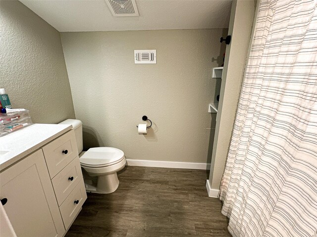 bathroom with a shower with shower curtain, a textured ceiling, vanity, hardwood / wood-style flooring, and toilet