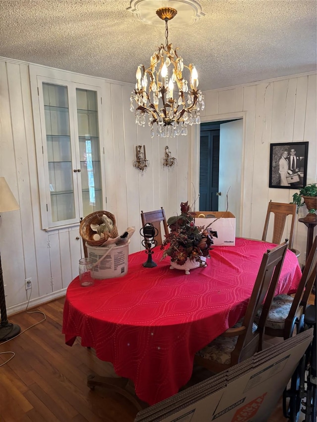 dining room with wood-type flooring, a chandelier, and a textured ceiling