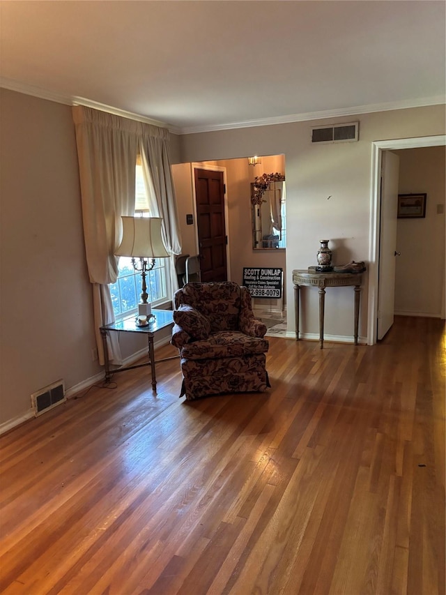 sitting room with hardwood / wood-style flooring and crown molding