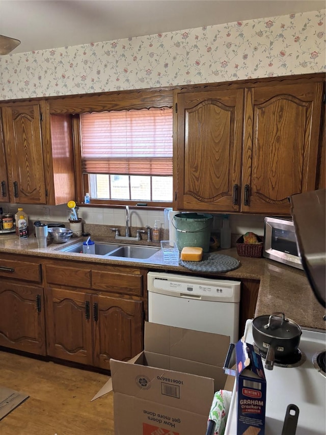 kitchen featuring dishwasher, sink, and light hardwood / wood-style floors