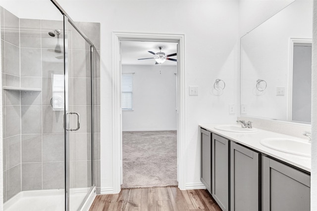 bathroom featuring hardwood / wood-style flooring, ceiling fan, a shower with door, and vanity