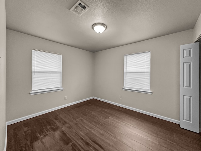 unfurnished room featuring a textured ceiling and dark hardwood / wood-style flooring