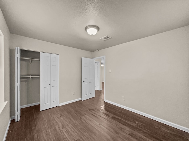 unfurnished bedroom featuring dark hardwood / wood-style floors, a textured ceiling, and a closet