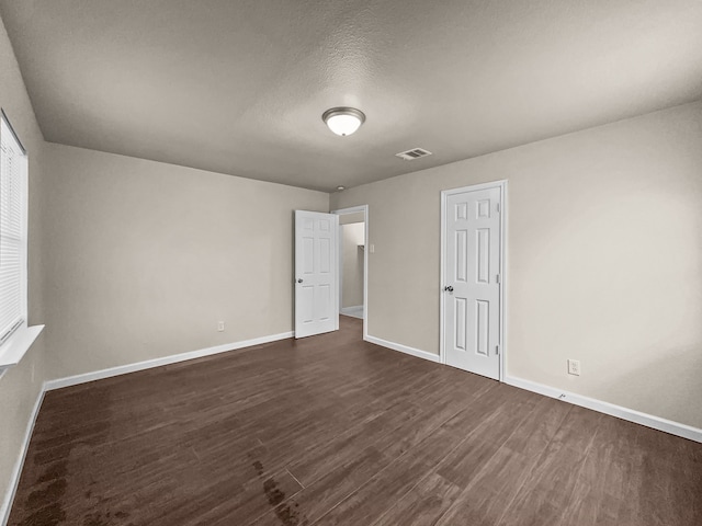 unfurnished room with dark wood-type flooring and a textured ceiling