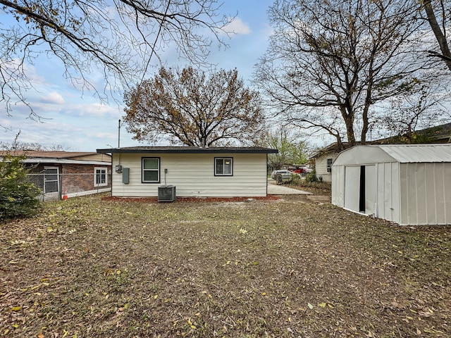 rear view of house with a lawn, central air condition unit, and a storage unit