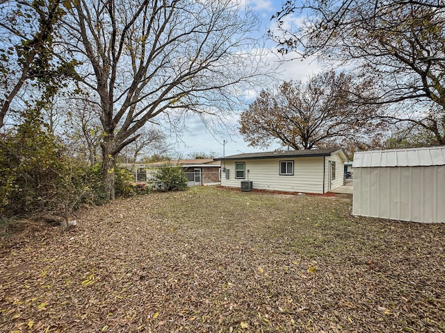 rear view of property with cooling unit and a shed