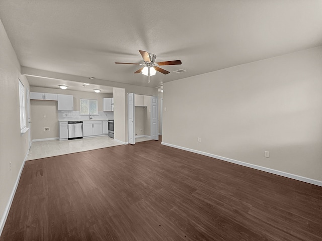 unfurnished living room with hardwood / wood-style flooring, ceiling fan, and sink