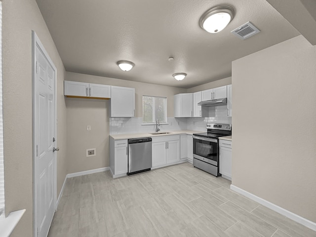 kitchen with white cabinetry, sink, stainless steel appliances, decorative backsplash, and light wood-type flooring