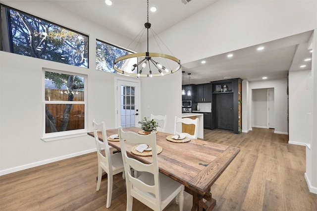 dining area featuring hardwood / wood-style floors, an inviting chandelier, and a high ceiling