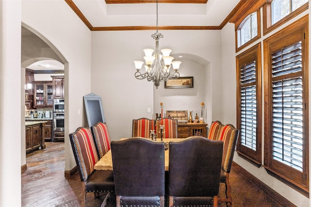 dining area featuring ornamental molding, dark hardwood / wood-style flooring, a tray ceiling, and a notable chandelier