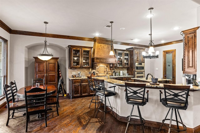 kitchen with premium range hood, light stone counters, hanging light fixtures, and dark hardwood / wood-style floors