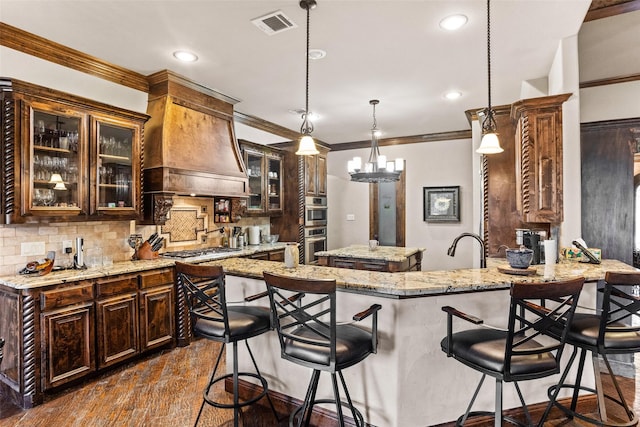 kitchen featuring light stone countertops, dark hardwood / wood-style flooring, kitchen peninsula, pendant lighting, and custom exhaust hood