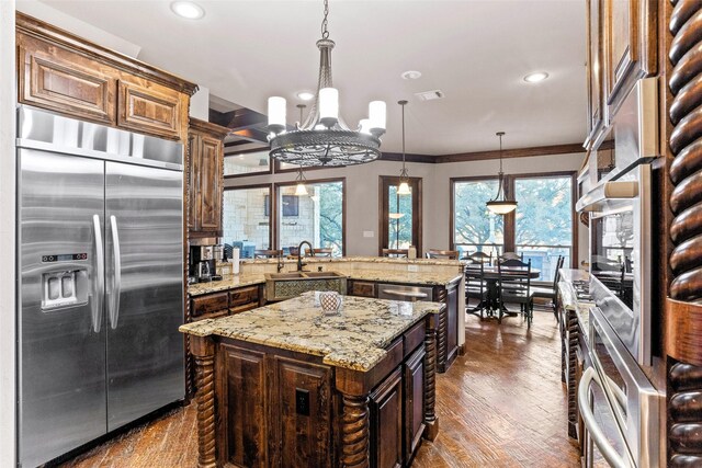 kitchen with a kitchen island, dark wood-type flooring, sink, built in refrigerator, and hanging light fixtures