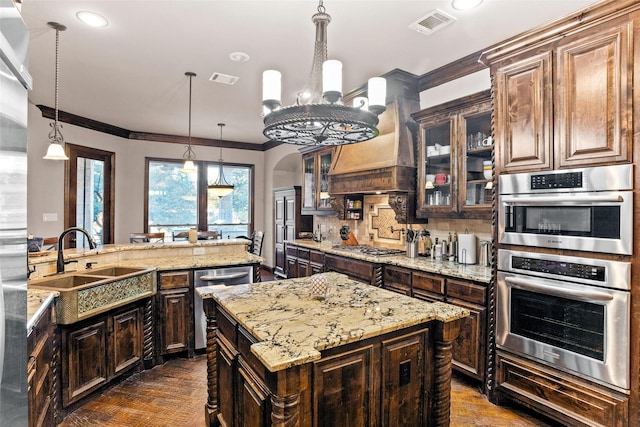 kitchen featuring a kitchen island, appliances with stainless steel finishes, dark brown cabinets, and hanging light fixtures