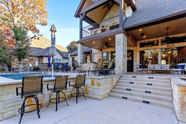 view of patio / terrace with ceiling fan, a balcony, a bar, and an outdoor hangout area