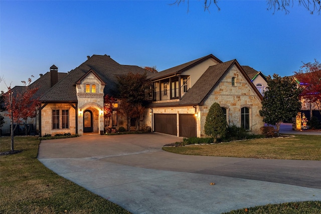 french provincial home with a garage, a lawn, and a balcony