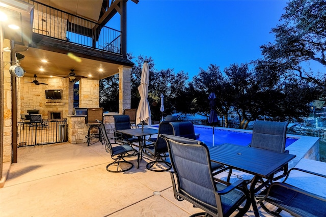 view of patio / terrace with a bar, ceiling fan, a balcony, and an outdoor stone fireplace