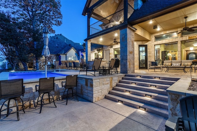 view of patio / terrace featuring pool water feature, ceiling fan, a balcony, and an outdoor living space