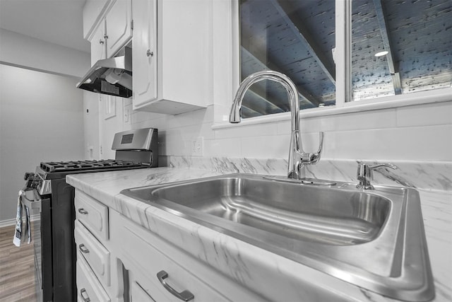 kitchen with white cabinets, sink, stainless steel gas range, hardwood / wood-style flooring, and tasteful backsplash