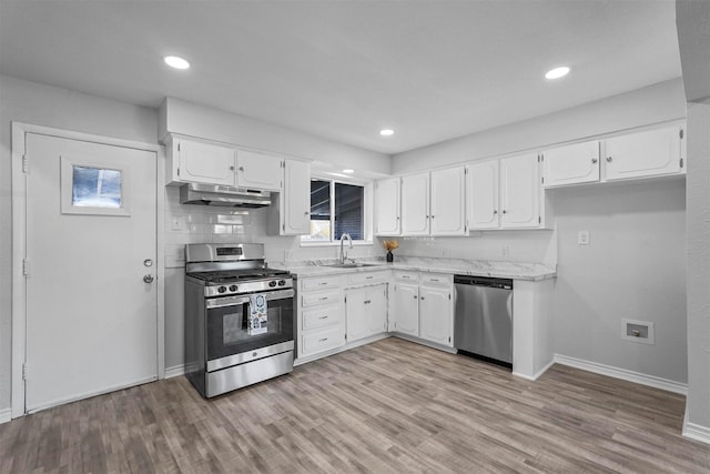 kitchen featuring sink, stainless steel appliances, backsplash, light hardwood / wood-style floors, and white cabinets