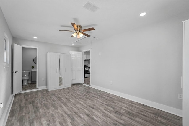 unfurnished bedroom featuring ceiling fan, ensuite bathroom, and hardwood / wood-style flooring