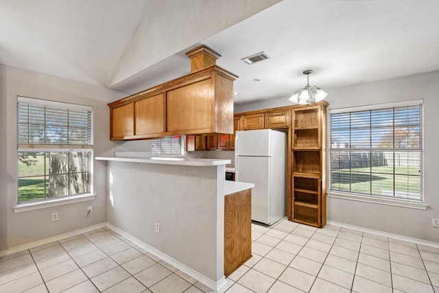 kitchen featuring white refrigerator, light tile patterned floors, kitchen peninsula, and a wealth of natural light