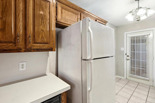 kitchen with a chandelier, light tile patterned floors, white refrigerator, and hanging light fixtures