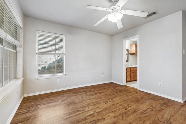 unfurnished bedroom featuring hardwood / wood-style floors, ensuite bath, and ceiling fan